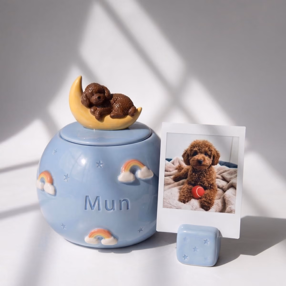 A deep blue ceramic pet urn painted with a crescent moon and scattered stars