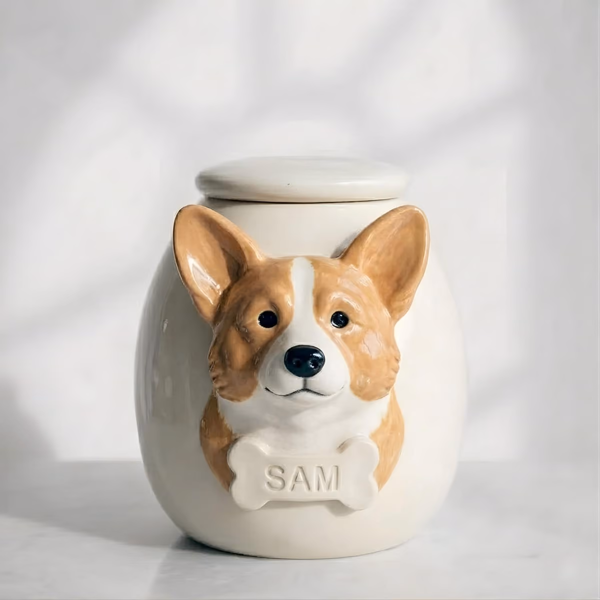 A ceramic urn with a Corgi face sculpted in relief and large upright ears