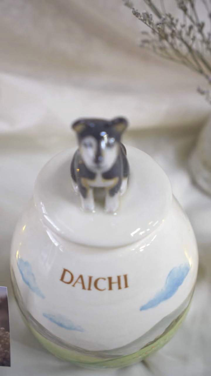 A finished ceramic urn with Daichi’s name on it, filmed beside a photo of Daichi