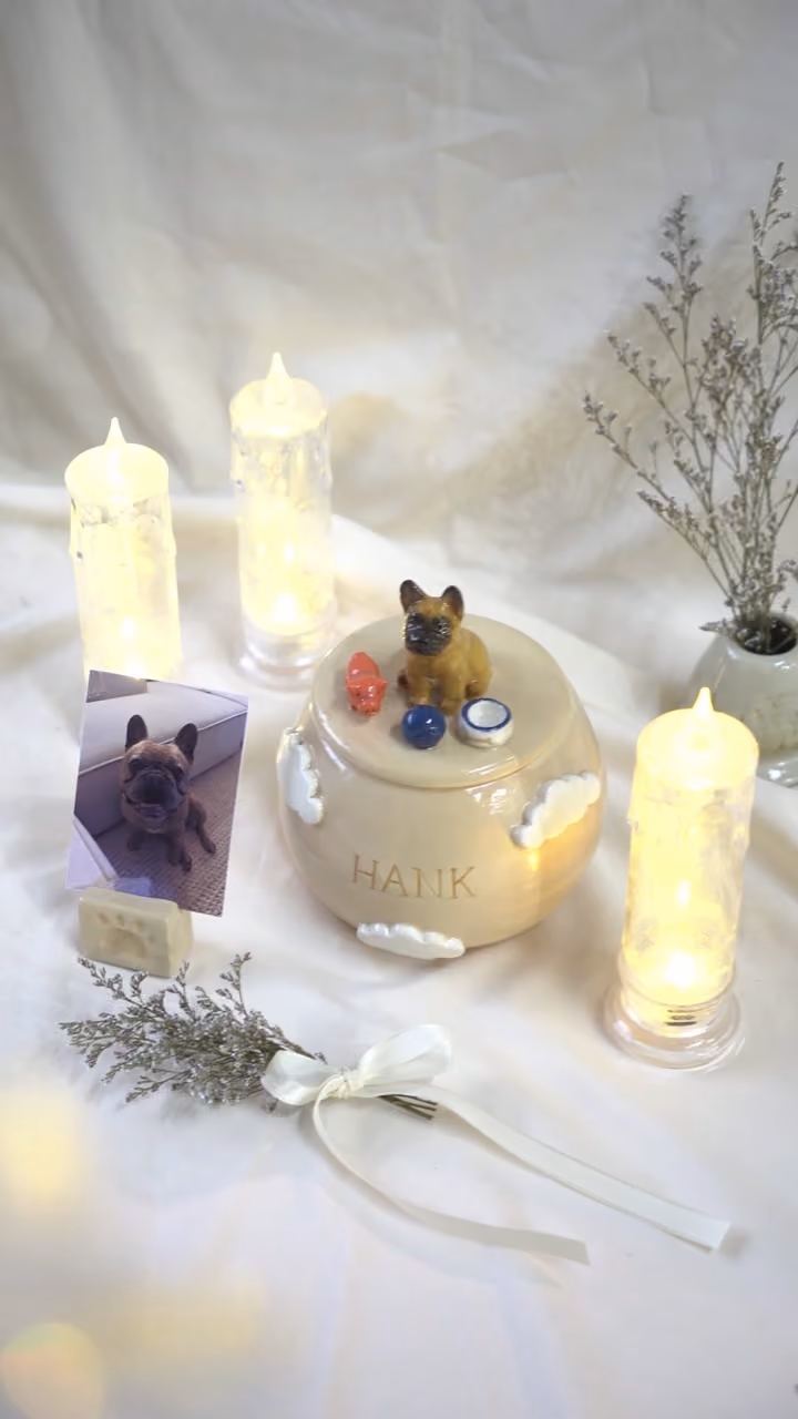 A finished ceramic urn with Hank’s name on it, filmed beside a photo of Hank