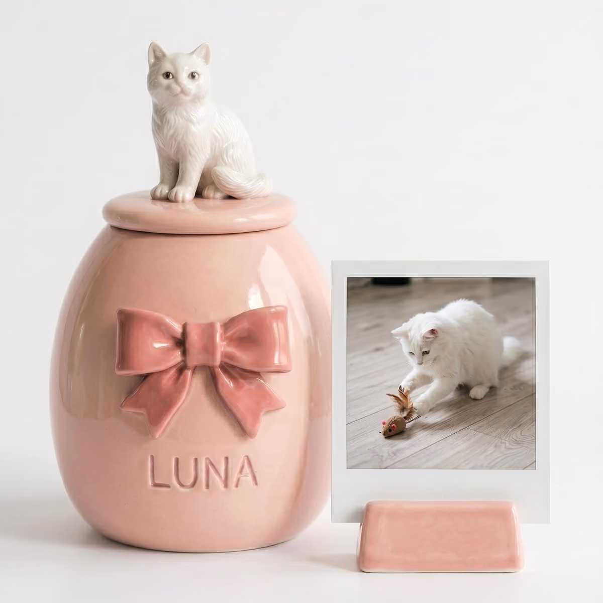 A pastel ceramic keepsake with a sculpted ribbon bow and an engraved name