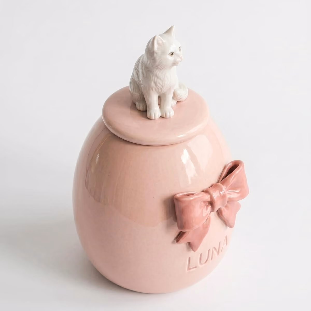 Heart & Bow pet urn shown next to a hand for scale