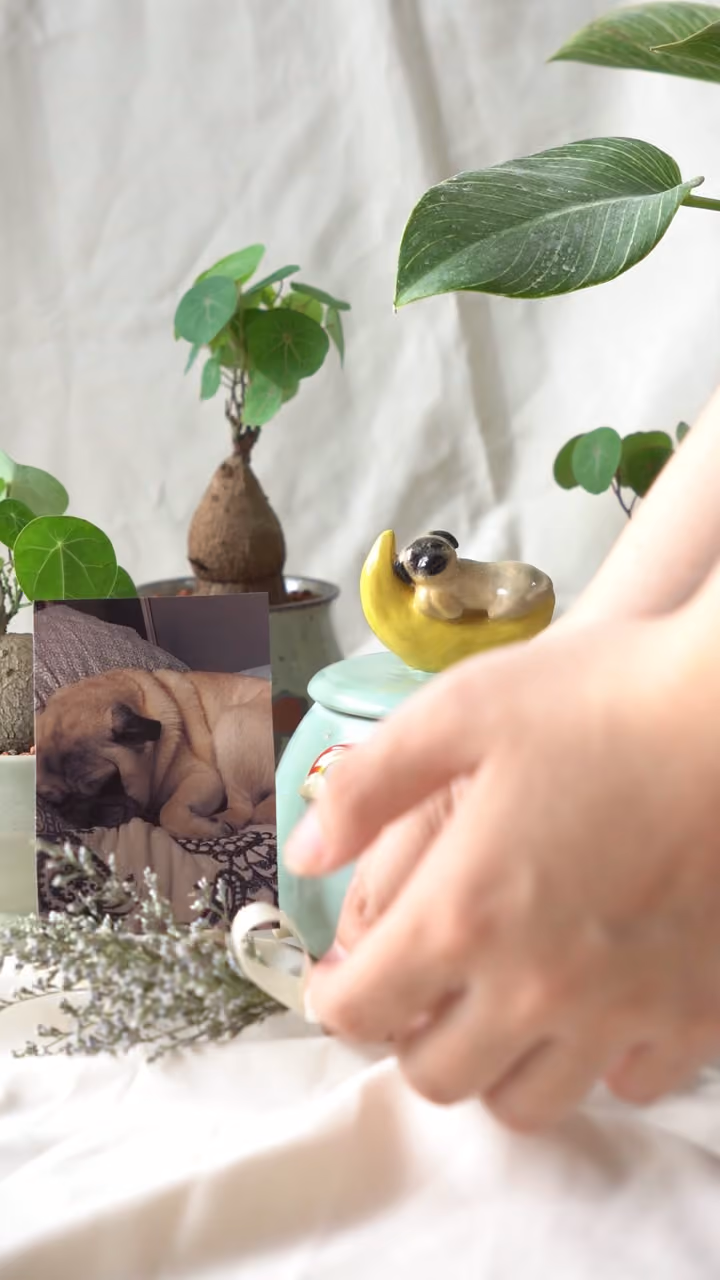 A finished ceramic urn with Jimmy’s name on it, filmed beside a photo of Jimmy