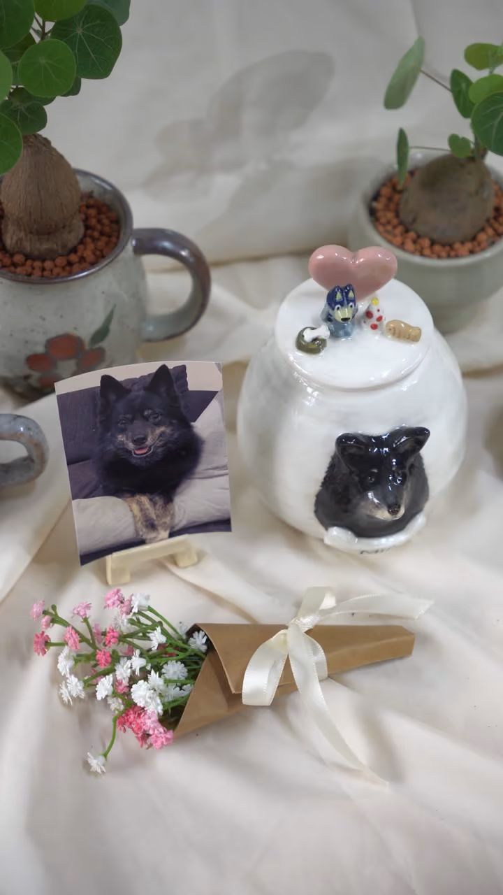 A finished ceramic urn with Mia’s name on it, filmed beside a photo of Mia