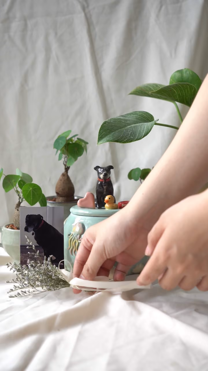 A finished ceramic urn with Mike’s name on it, filmed beside a photo of Mike