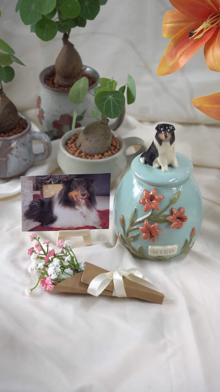 A finished ceramic urn with Miko’s name on it, filmed beside a photo of Miko