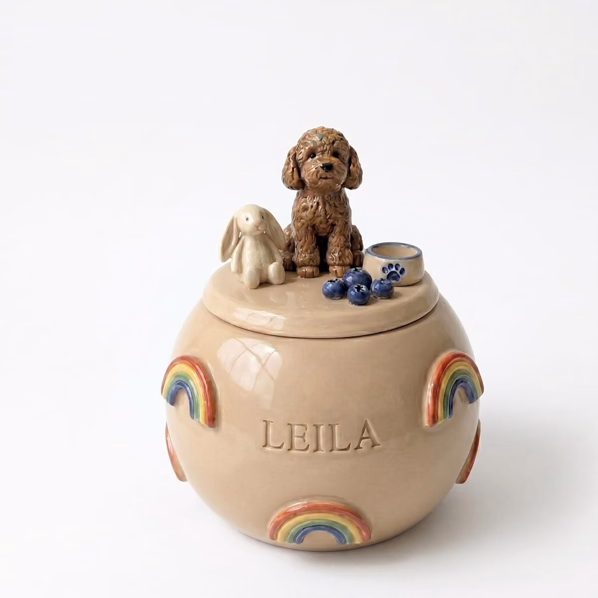 A ceramic pet urn painted with a soft watercolour rainbow arc