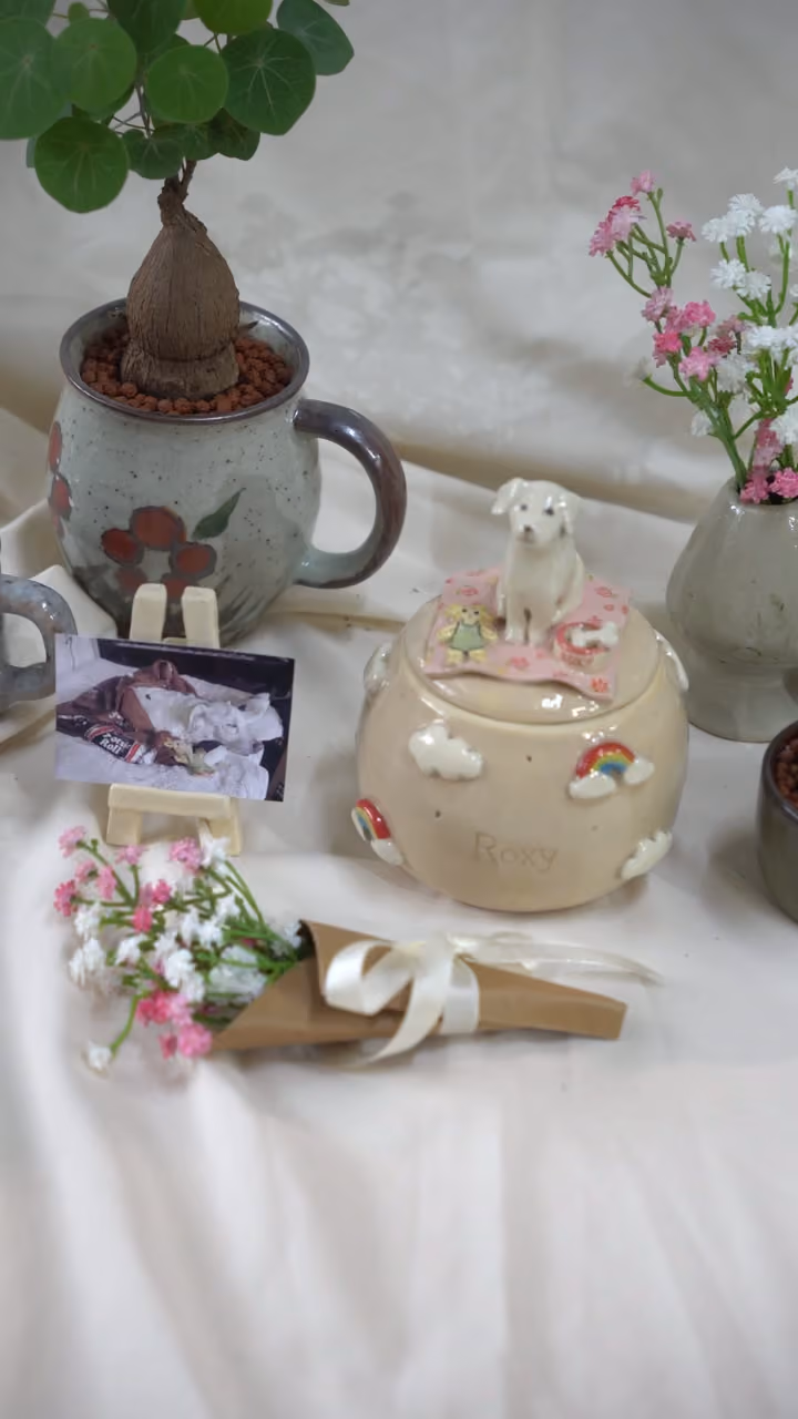 A finished ceramic urn with Roxy’s name on it, filmed beside a photo of Roxy