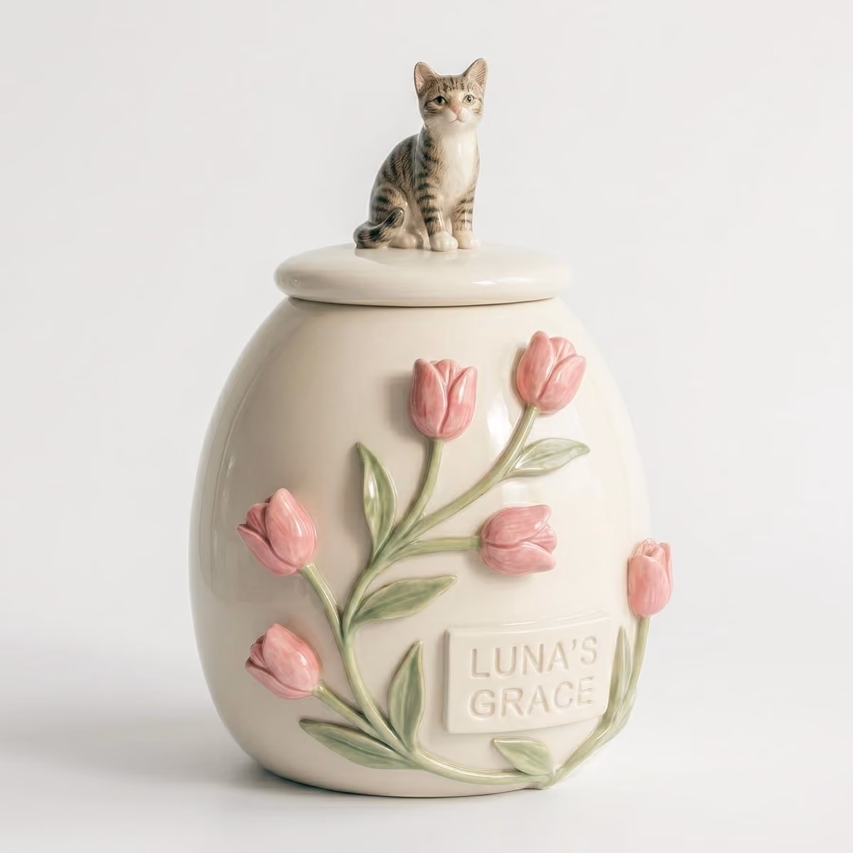 A ceramic pet urn with a sitting tabby cat figurine sculpted on the lid